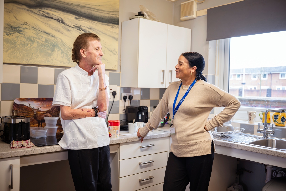 A officer speaking to a customer in a kitchen.